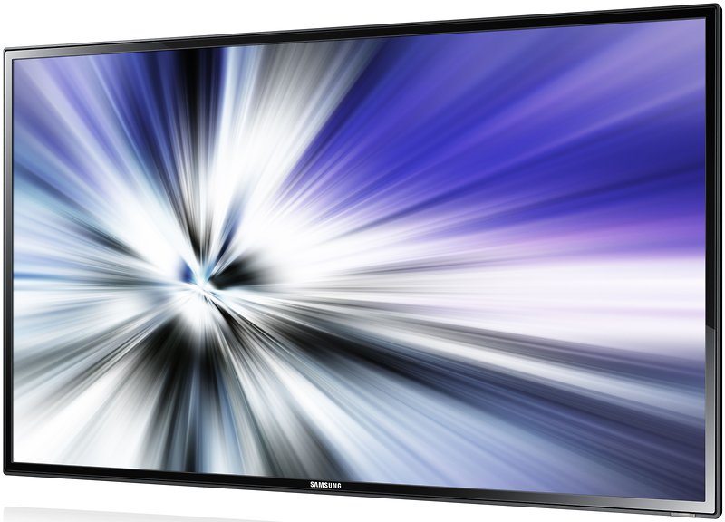 Samsung ME65B 65 Inch LED LCD rental TV with a slim, modern design, shown from a side angle displaying a vibrant abstract burst of blue, white, and black light on screen.