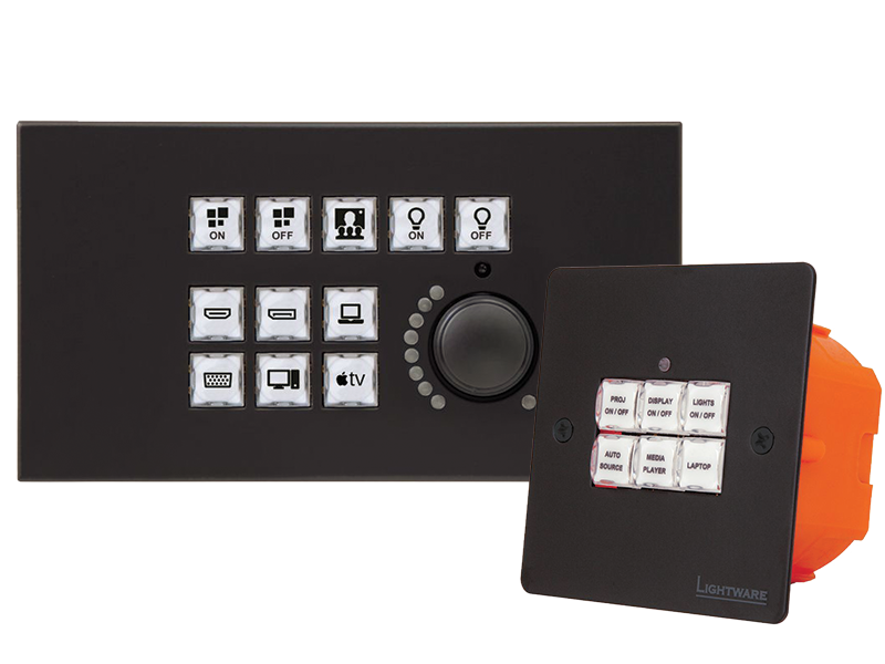 Two black wall-mounted AV control panels with labeled buttons and a rotary knob. The buttons display icons for on/off, display, lights, laptop, HDMI, and Apple TV inputs. Ideal for managing multimedia devices in conference rooms or classrooms.