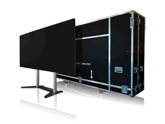 Optoma QUADShow LED All-in-One Display on a stand next to a black wheeled shipping case; the display is newly purchased and designed for easy transport and setup.
