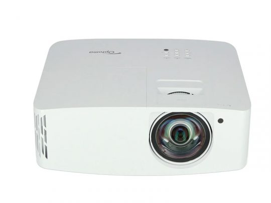 White Optoma projector with a large front lens, side air vents, and top control buttons, shown from a slightly elevated front angle.