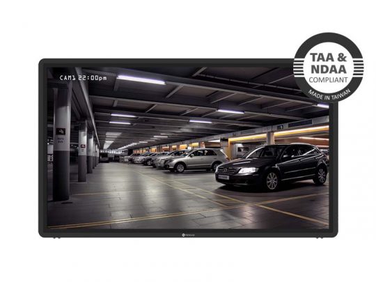 Security camera monitor displaying clear footage of a brightly lit indoor parking garage with multiple parked cars; top right badge states TAA & NDAA Compliant - Made in Taiwan, indicating the security system meets US government standards.