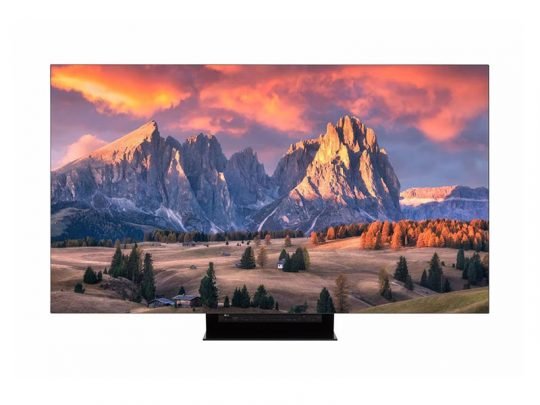 Flachbildfernseher, Modell zeigt auf dem Bildschirm ein farbenfrohes Bergpanorama bei Sonnenuntergang mit dramatischen Wolken, sonnenbeschienenen Gipfeln und einem grünen Tal mit Bäumen und Häusern - ideal für detailreiche TV-Erlebnisse.