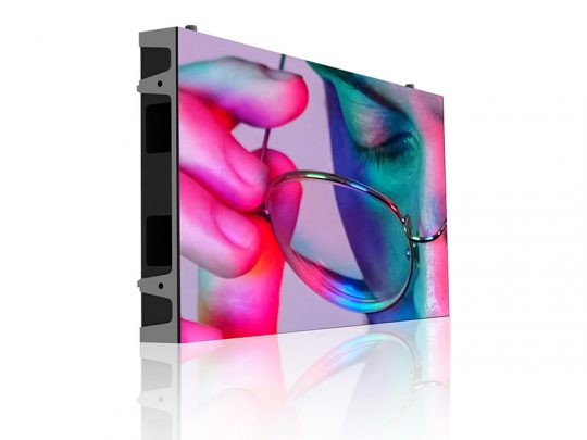 Ultradünnes LED-Display zeigt Nahaufnahme eines Gesichts mit bunter Beleuchtung und einer gehaltenen Brille; das Display steht auf glänzender, weißer Oberfläche. Ideal für hochauflösende Werbepräsentationen und moderne Innenraumgestaltung.
