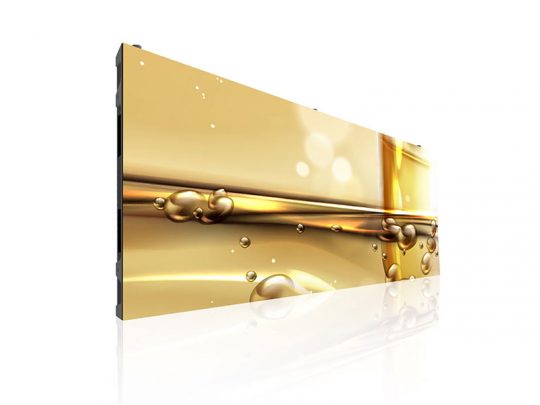 Moderner, großformatiger Flachbildschirm - vermutlich ein Samsung TV - zeigt eine Nahaufnahme von goldener, sprudelnder Flüssigkeit (ähnlich Öl) vor weißem Hintergrund, mit spiegelnder Reflexion am glänzenden Boden.