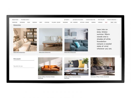 Computerbildschirm mit geöffneter Website, die moderne Wohnzimmermöbel wie Sofas und Ecksofas (Sectionals) präsentiert; auf der Seite sind Produktbilder, Beschreibungen und eine Sidebar mit Tipps zu sommerlicher Einrichtung zu sehen.